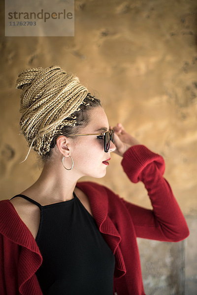 Junge Frau mit Dreadlocks  im Freien  Sonnenbrille aufsetzen