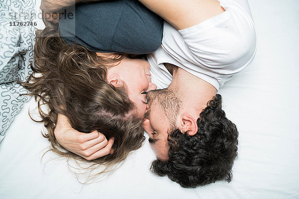 Draufsicht auf ein junges Paar  das im Bett liegt und sich umarmt