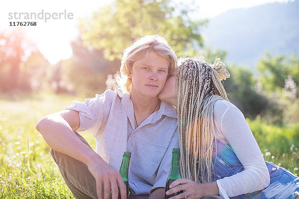 Romantisches junges Paar sitzt im Feld bei Flaschenbier  Mallorca  Spanien