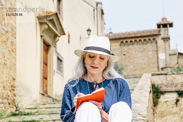 Stilvolle  reife Frau schreibt in Notizbuch vor der Kirche  Fiesole  Toskana  Italien