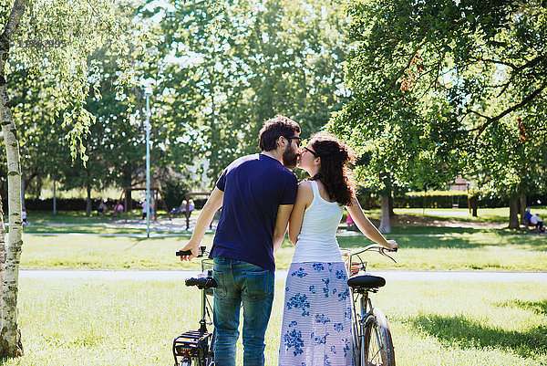 Rückansicht eines Paares mit sich küssenden Fahrrädern im Park  Arezzo  Toskana  Italien