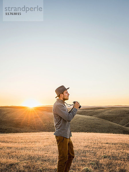 Mann mit Fernglas in den sanften Hügeln der Prärie  Bakersfield  Kalifornien  USA