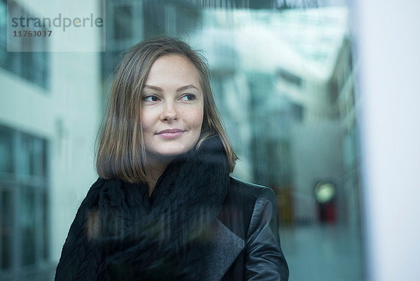 Bürofenster-Porträt einer jungen Geschäftsfrau mit Blick zur Seite