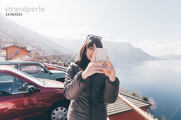 Mittelgroße erwachsene Frau mit Smartphone-Selfie am Seeufer  Monte San Primo  Italien