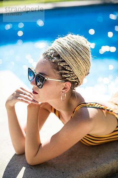 Junge Frau mit Dreadlocks  die sich am Swimmingpool entspannt