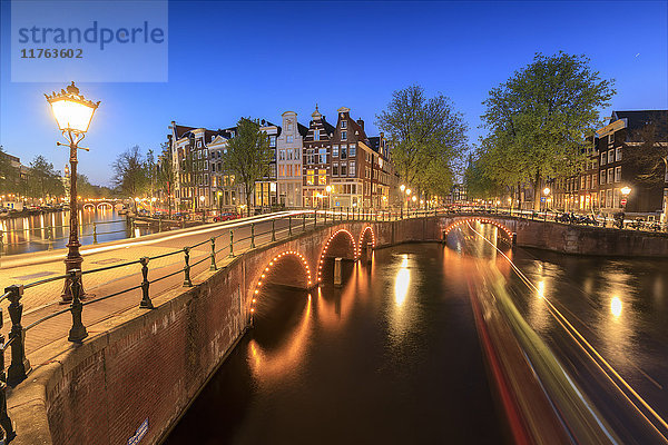Dämmerungslichter auf typischen Gebäuden und Brücken  die sich in einer typischen Gracht spiegeln  Amsterdam  Holland (Niederlande)  Europa