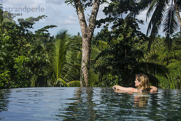 Frau genießt einen überlaufenden Pool oberhalb eines Tals im Kamandalu Ubud Resort  Ubud  Bali  Indonesien  Südostasien  Asien