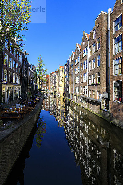Typische Häuser  die sich im blauen Wasser einer Gracht spiegeln  Amsterdam  Holland (Niederlande)  Europa