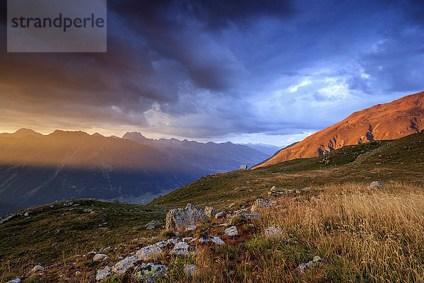 Feuriger Himmel und dunkle Wolken auf den hohen Gipfeln von Muottas Muragl bei Sonnenuntergang  St. Moritz  Kanton Graubünden  Engadin  Schweiz  Europa