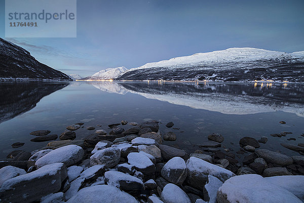 Schneebedeckte Gipfel spiegeln sich im kalten Meer in der Abenddämmerung  Manndalen  Kafjord  Lyngen Alps  Troms  Norwegen  Skandinavien  Europa