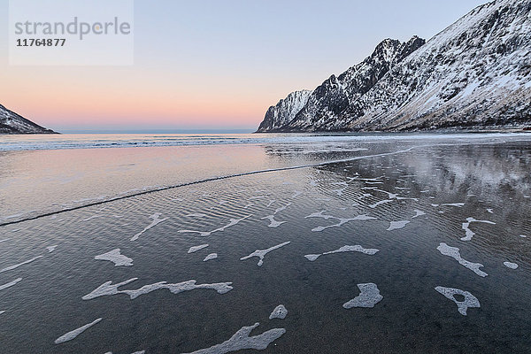 Das rosa Licht des Sonnenaufgangs über den Wellen des kalten Meeres  umgeben von schneebedeckten Gipfeln  Ersfjord  Senja  Troms  Norwegen  Skandinavien  Europa