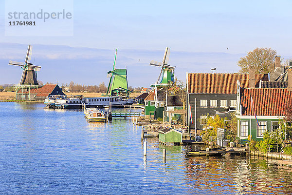 Holzhäuser und Windmühle spiegeln sich im blauen Wasser des Flusses Zaan  Zaanse Schans  Nordholland  Niederlande  Europa