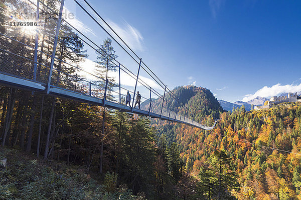 Touristen auf der Hängebrücke Highline 179  umrahmt von bunten Wäldern im Herbst  Schloss Ehrenberg  Reutte  Österreich  Europa