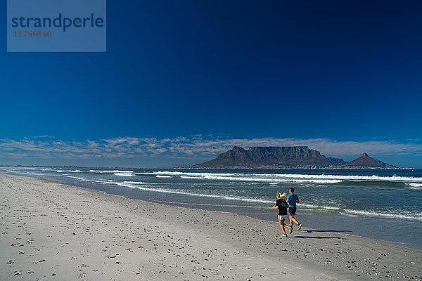 Jogger  die am frühen Morgen am Blouberg Beach laufen  mit dem Tafelberg im Hintergrund  Kapstadt  Südafrika  Afrika