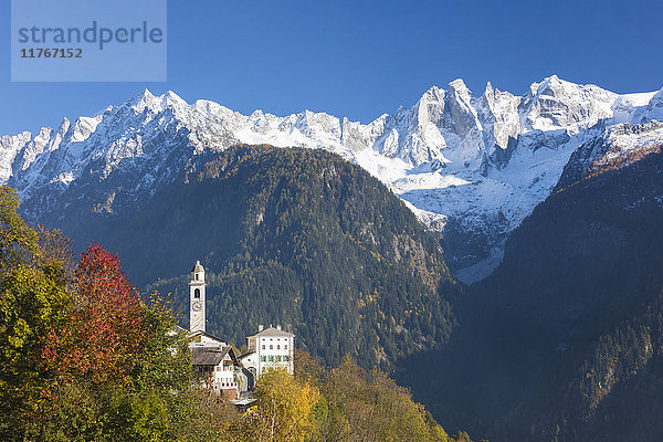 Die bunten Bäume umrahmen die Alpenkirche und die verschneiten Gipfel  Soglio  Bergell  Kanton Graubünden  Schweizer Alpen  Schweiz Europa