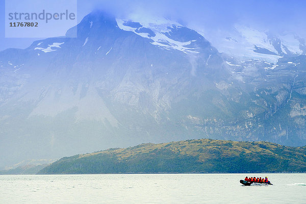 Dinghy in einem Fjord im Alberto de Agostini Nationalpark mit der Darwin-Bergkette (Cordillera Darwin) im Hintergrund  Patagonien  Chile  Südamerika