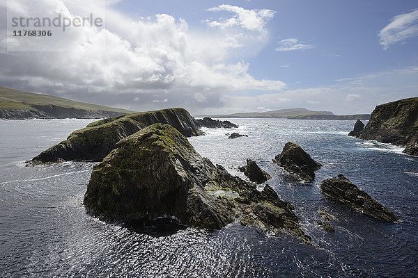 Riesige Wolken machen den Weg frei für strahlenden Sonnenschein  der die Klippen und Inseln der St. Ninian's Bay beleuchtet  Shetland  Schottland  Vereinigtes Königreich  Europa