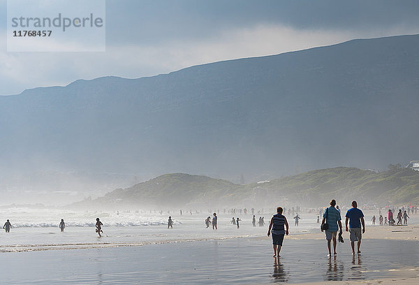Menschen  die im späten Nachmittagslicht am Hauptstrand und im Meer spazieren gehen  Hermanus  Südafrika  Afrika