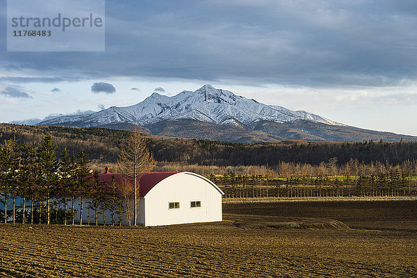Kleiner Bauernhof vor einem schneebedeckten Berg in der Nähe des Shiretoko-Nationalparks  Hokkaido  Japan  Asien