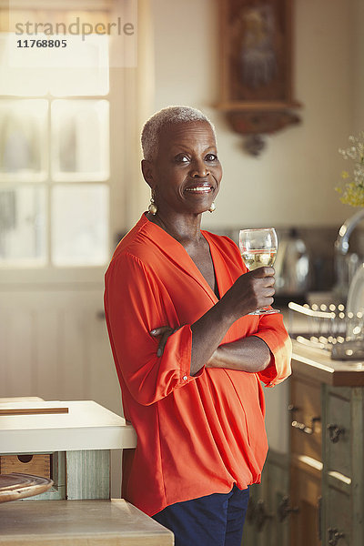 Portrait lächelnde Seniorin beim Weintrinken in der Küche
