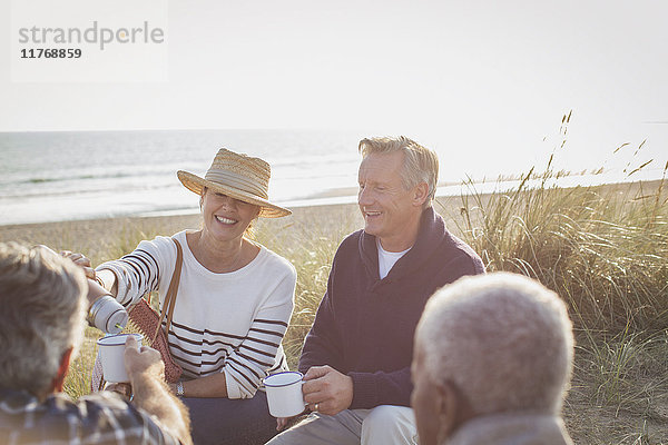 Seniorenpaare trinken Kaffee am sonnigen Strand