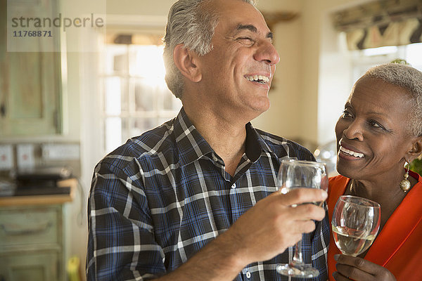 Lachendes Seniorenpaar trinkt Weißwein
