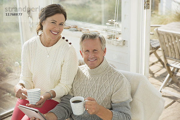 Portrait lächelndes reifes Paar mit digitalem Tablett und Kaffeetrinken auf der Sonnenterrasse