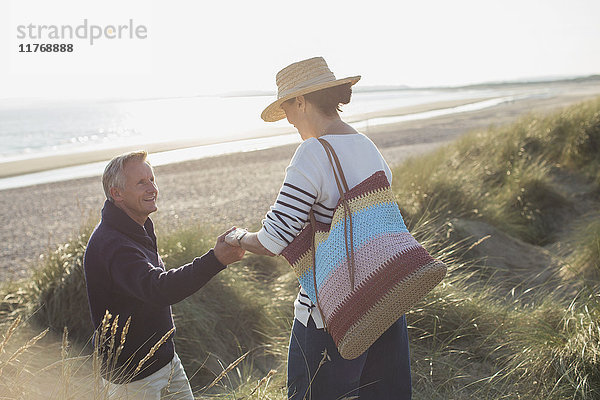 Ehemann hilft Frau auf sonnigem Strandgrasweg