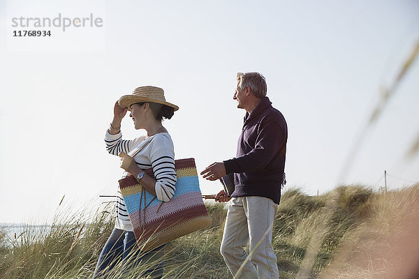 Erwachsenes Paar  das auf einem sonnigen Strandgrasweg spazieren geht.