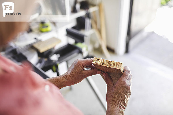 Abgeschnittenes Bild einer älteren Frau mit Holzbrettern in der Werkstatt