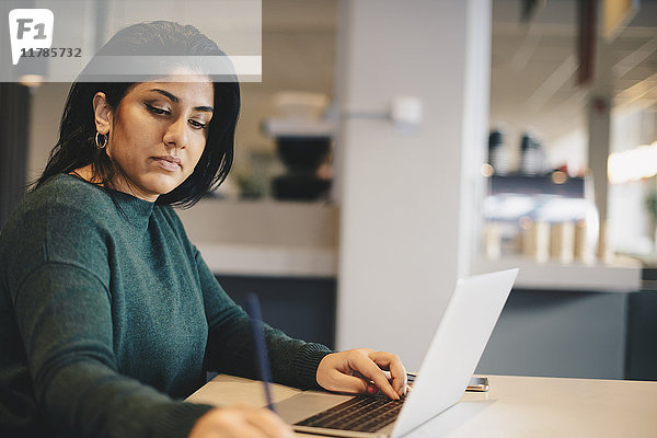 Geschäftsfrau beim Schreiben mit dem Laptop am Schreibtisch im Büro