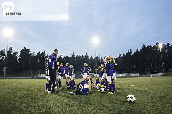 Trainerin steht bei weiblicher Fußballmannschaft auf dem Feld gegen den Himmel