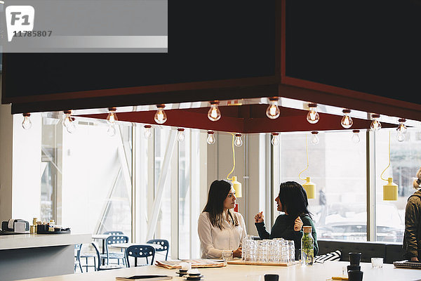 Geschäftsfrauen diskutieren bei Tisch im hell erleuchteten Büro