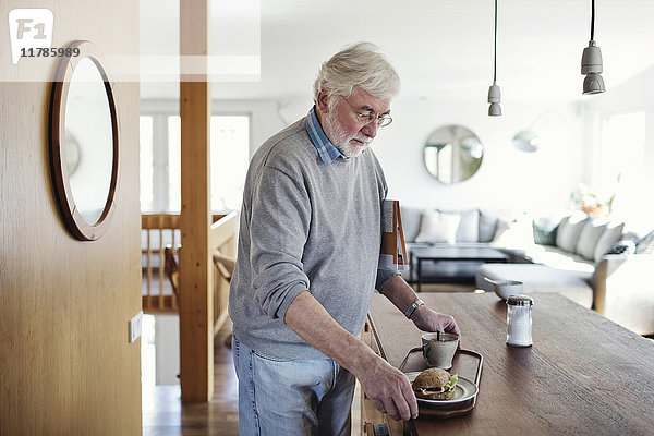 Senior Mann mit Frühstück im Tablett zu Hause