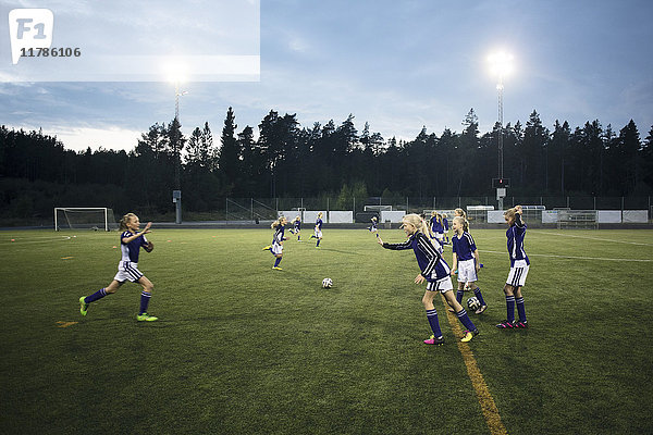 Mädchen laufen auf dem Fußballfeld gegen den Himmel
