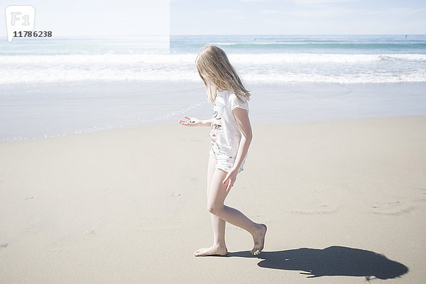 Seitenansicht des Mädchens mit Stein beim Spaziergang am Strand