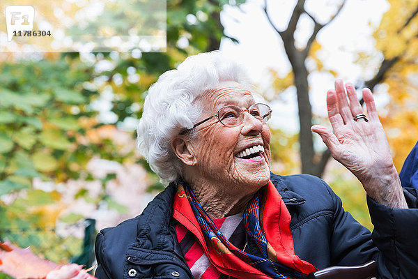 Fröhliche Seniorin  die im Herbst im Park gestikuliert.