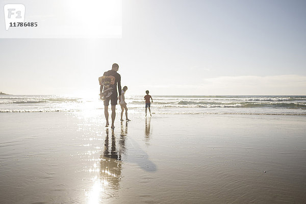 Vater und Kinder genießen Urlaub am Strand an einem sonnigen Tag