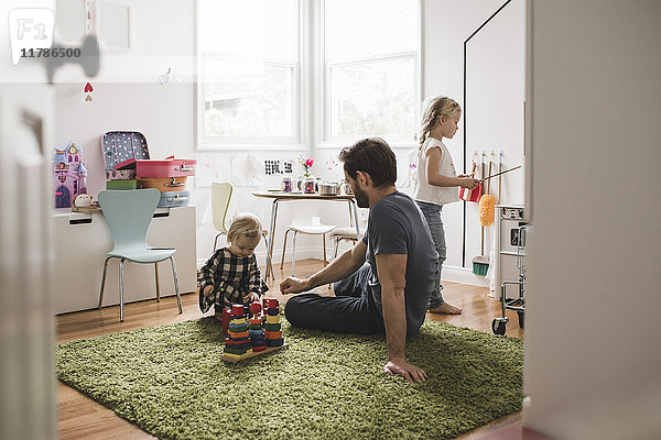 Vater und Töchter spielen mit Spielzeug im Spielzimmer zu Hause