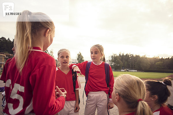 Mädchen in roter Fußballuniform sprechen gegen den Himmel