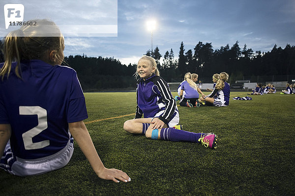 Mädchen entspannen sich auf dem Fußballplatz gegen den Himmel