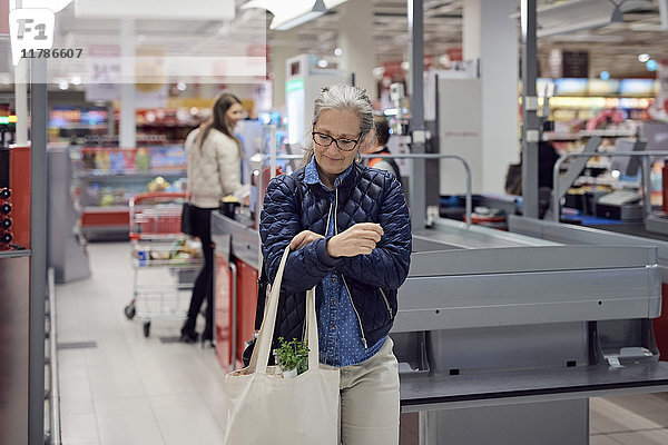 Lächelnde reife Frau mit Einkaufstasche im Supermarkt