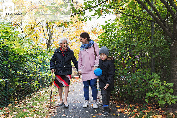 Volle Länge der glücklichen älteren Frau  die mit Tochter und Urenkel im Park läuft.