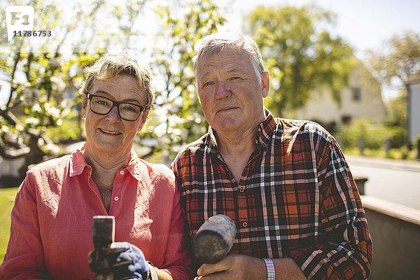 Porträt eines selbstbewussten Seniorenpaares mit Hämmern auf dem Hof