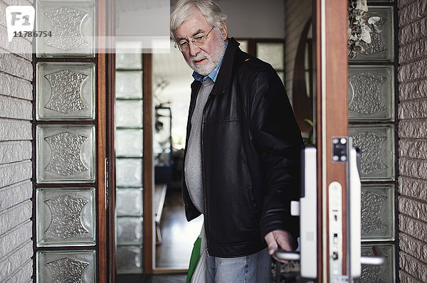 Senior Mann mit Lederjacke und schliessender Tür