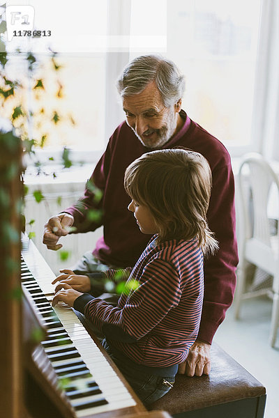 Glücklicher älterer Mann im Gespräch mit Urgroßvater  der zu Hause Klavier spielt.