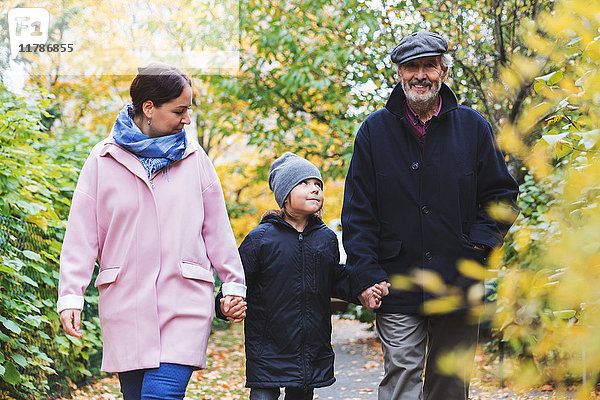 Fröhlicher Senior mit Urenkel und Tochter im Herbst im Park unterwegs