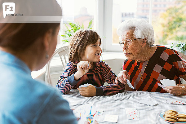 Glücklicher Junge zeigt Spielkarte mit Urgroßmutter zu Hause