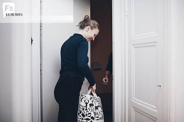 Glückliche Frau mit Einkaufstasche an der Tür