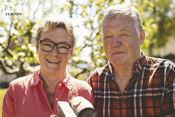Porträt eines glücklichen älteren Ehepaares mit Hämmern auf dem Hof